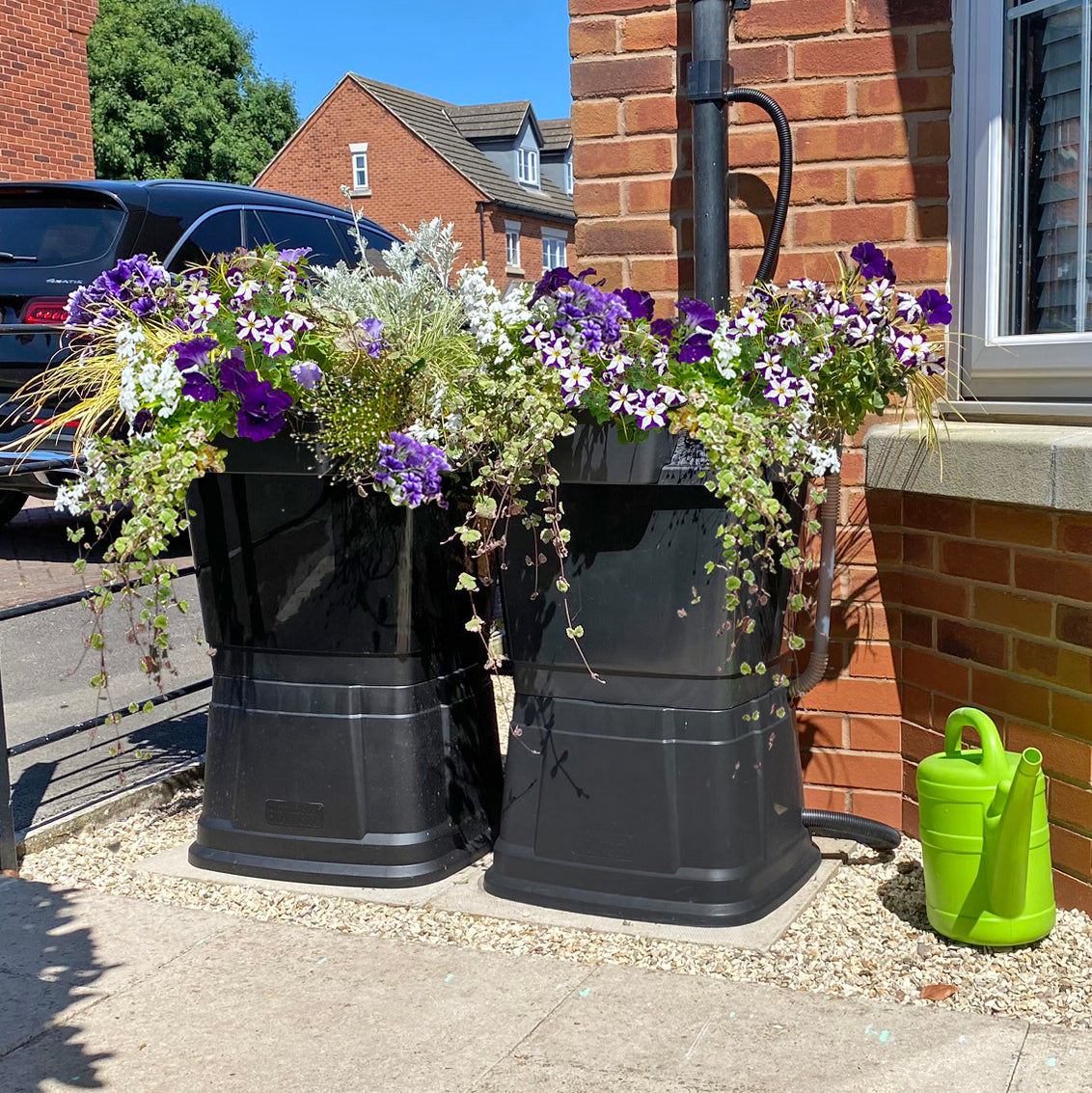 black 134 litre water butt attached to downpipe at the front of a house